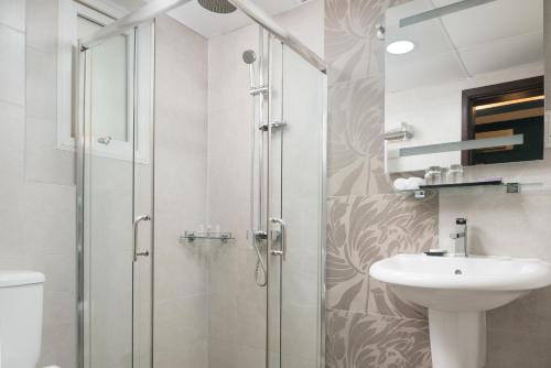 uma casa de banho com um chuveiro e um lavatório. em Al Hail Waves Hotel Managed By Centara em Seeb