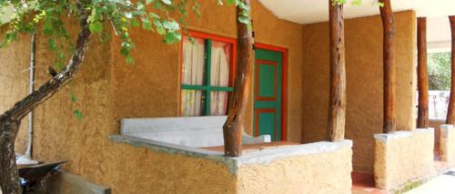 um edifício com uma porta verde e vermelha e árvores em Clay Hut Village em Pollonaruva