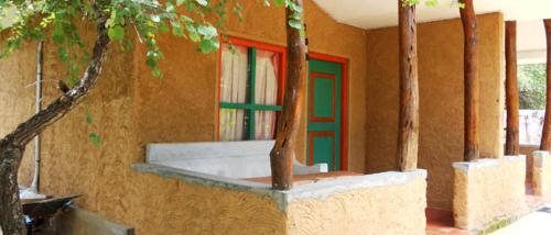 a building with a green and red door and trees at Clay Hut Village in Polonnaruwa