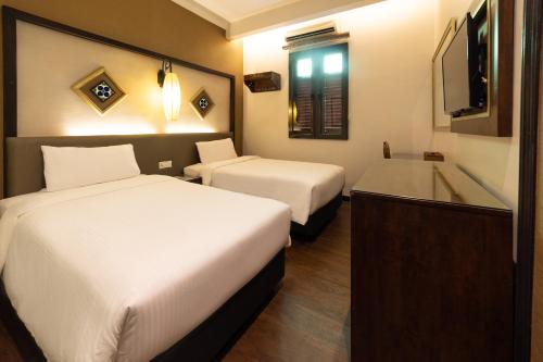 a hotel room with two beds and a bathtub at Hotel Puri Melaka in Malacca