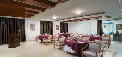 a dining room with purple tables and chairs at Al Hail Waves Hotel Managed By Centara in Seeb