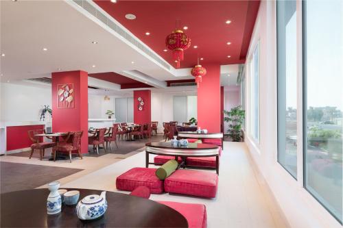 a lobby with red walls and tables and chairs at Al Hail Waves Hotel Managed By Centara in Seeb