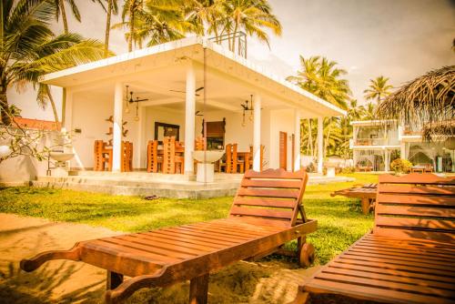 two wooden benches sitting in front of a house at Infinity of Sri Lanka in Paiyagala South