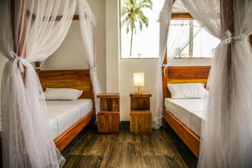 a bedroom with two beds with drapes and a window at Infinity of Sri Lanka in Paiyagala South