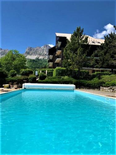 une grande piscine d'eau bleue devant un bâtiment dans l'établissement SCI jsm, à Gresse-en-Vercors