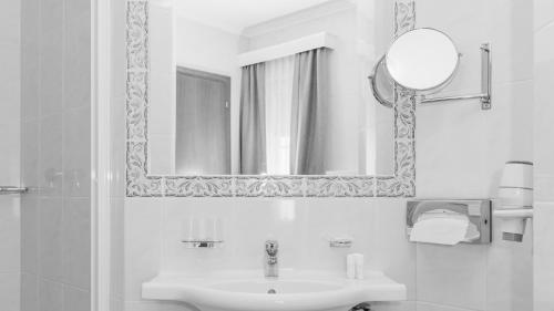 Baño blanco con lavabo y espejo en Hotel24Steps, en Ischgl