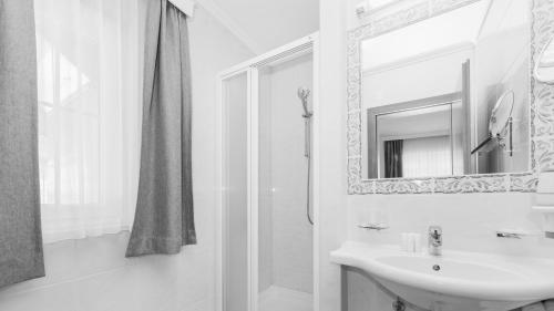 a white bathroom with a sink and a mirror at Hotel24Steps in Ischgl