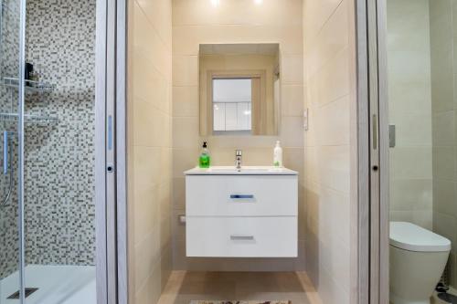 ein Badezimmer mit einem weißen Waschbecken und einer Dusche in der Unterkunft CB Living - Modern apartment, Terrazas de Campoamor in Orihuela