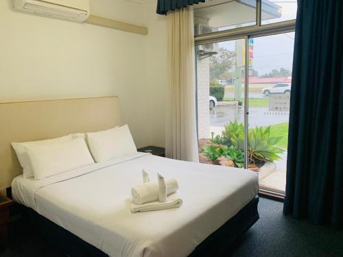 1 dormitorio con 1 cama con 2 toallas en Lake Munmorah Motel, en Lake Munmorah