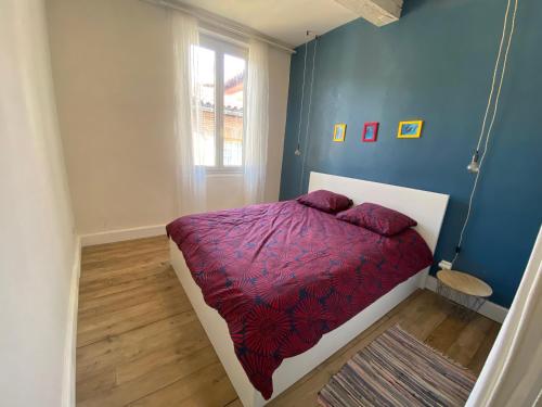 - une chambre avec un lit doté d'une couette violette et d'une fenêtre dans l'établissement Maison médiévale Albigeoise en centre ville, à Albi