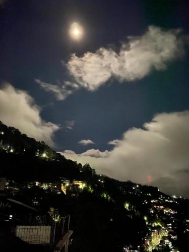 a view of a city at night with the moon at MAMTA HOMESTAY in Darjeeling