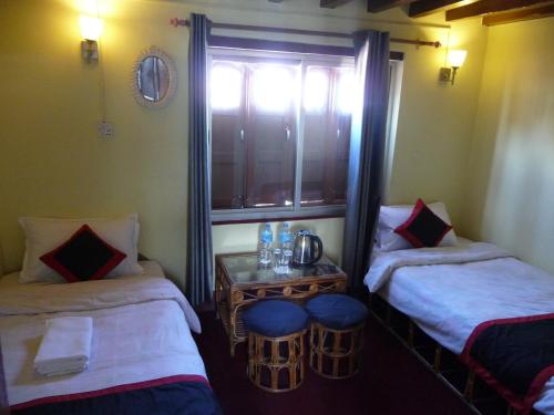 a room with two beds and a table and a window at HOTEL RUPAKOT AND ROOFTOP RESTAURANT in Bhaktapur