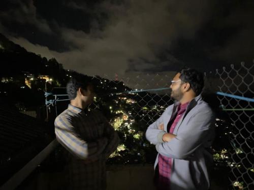 two men standing on top of a fence at night at MAMTA HOMESTAY in Darjeeling