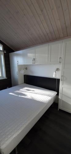 Cama blanca en habitación con techo en Lakeside log cabin Främby Udde Falun, en Falun