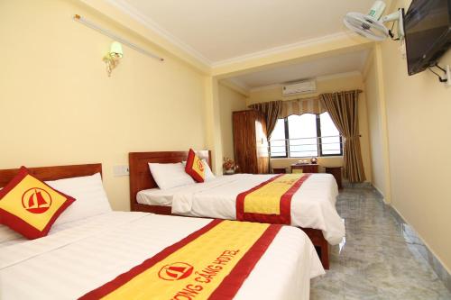 a hotel room with two beds and a flat screen tv at Huong Cang Sea View Hotel in Cat Ba