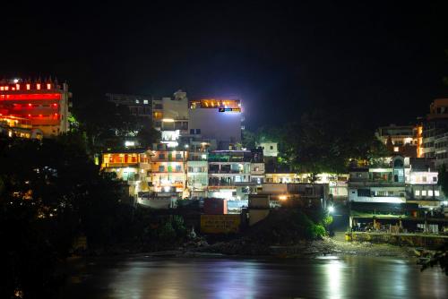 Una ciudad iluminada por la noche junto a un río en Madpackers Rishikesh Ganga View en Rishīkesh