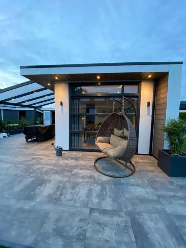 a wicker chair sitting on top of a patio at LUXUS Cube Ferienhaus Chalet am See mit Schwimmbad in Lathum NL in Lathum