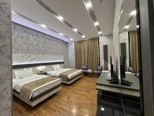 1 Schlafzimmer mit 2 Betten und einem Schreibtisch mit einem TV in der Unterkunft Ada Hotel in Taschkent