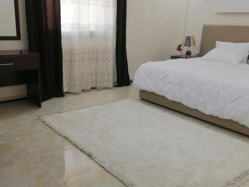 a bedroom with a white bed and a rug at Petra Guests home in Wadi Musa