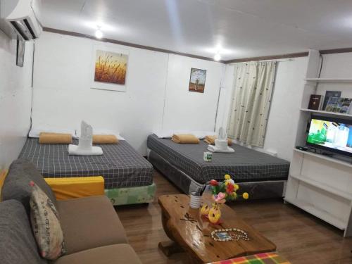 sala de estar con 2 camas y sofá en Okoy Guest House, en Bantayan Island