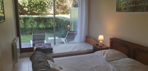 a bedroom with two beds and a window with chairs at Appartement standing front de mer Arcachon in Arcachon