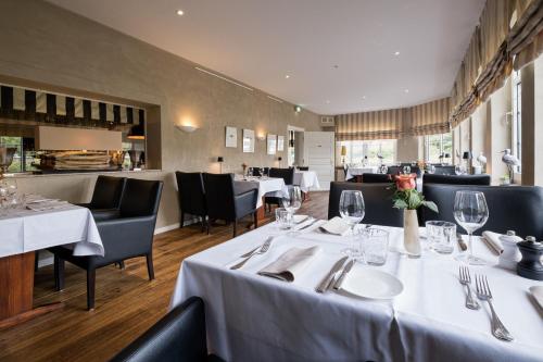 uma sala de jantar com mesas e cadeiras brancas e um restaurante em Eichhorns em Niebüll