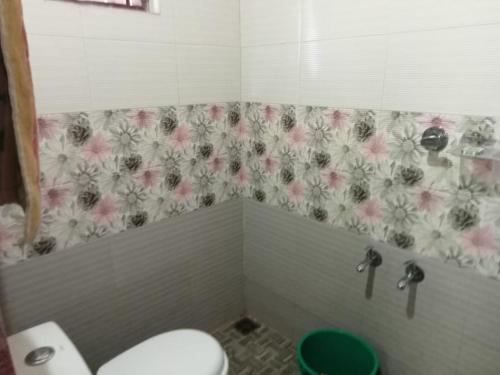 a bathroom with a toilet and a flower shower curtain at SanSree's Puzhakkal Homestay in Wayanad