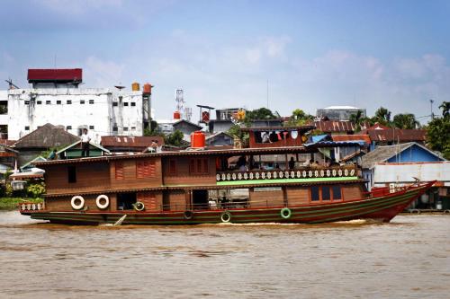 a large wooden boat in the water on a river at Hotel Luwansa Palangkaraya in Palangkaraya