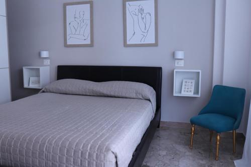 ein Schlafzimmer mit einem Bett und einem blauen Stuhl in der Unterkunft Due Passi dal Mare in Pescara