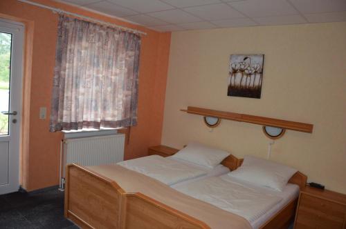 1 dormitorio con 2 camas y ventana en Hotel-Garni "Hof von Hannover", en Wittmund