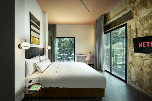 Habitación de hotel con cama y balcón en Pixel Dizengoff Square - Smart Hotel by Loginn Tel Aviv, en Tel Aviv