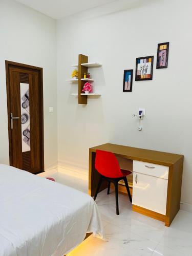 a bedroom with a desk and a bed and a red chair at Milaano Orchids, Service Villa, Kammana Mananthavady in Wayanad