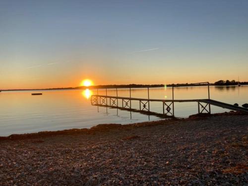 a dock on a lake with the sunset in the background at jygge- hyggelige Ferienwohnung in Nordborg