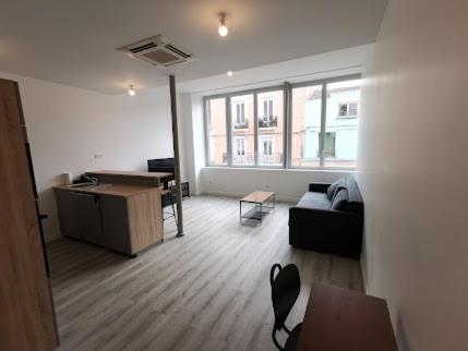 een grote woonkamer met een bank en een bureau bij 10 rue Carnot in Montceau-les-Mines