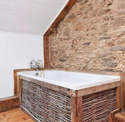 une baignoire dans une pièce avec un mur en pierre dans l'établissement La querelle, à Gorre