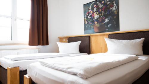 2 łóżka w pokoju hotelowym z białą pościelą w obiekcie Hotel Am Hopfenmarkt w mieście Rostock