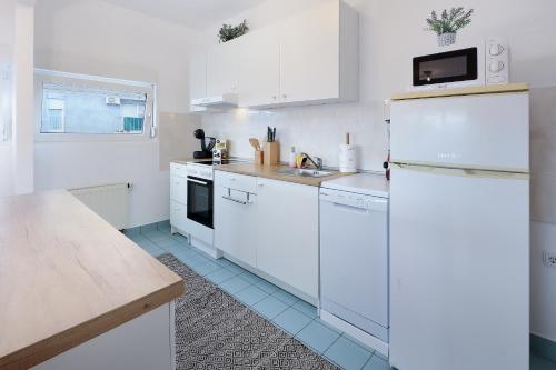 een witte keuken met witte kasten en een wastafel bij Apartment Leon - Sea View in Rijeka