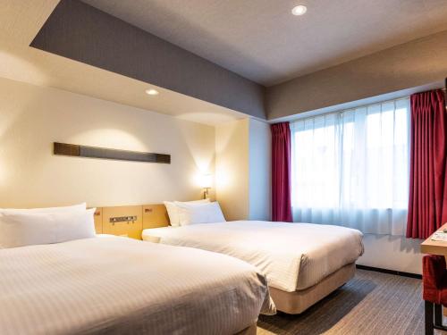 a hotel room with two beds and two lamps at ibis Styles Kyoto Station in Kyoto