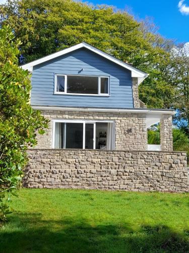 a blue house with a stone wall at Fairwater Head in Axminster
