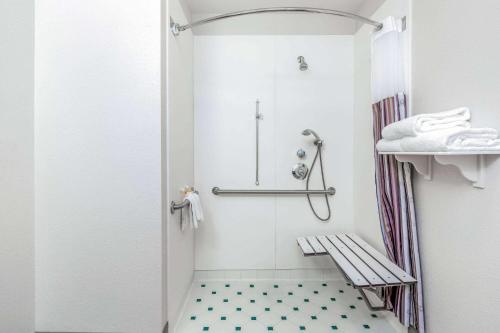 a white bathroom with a shower and a bench at La Quinta by Wyndham Fremont / Silicon Valley in Fremont