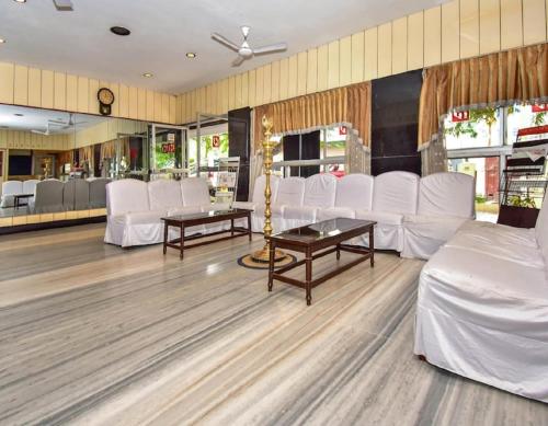 - une salle d'attente avec des tables et des chaises blanches dans l'établissement Hotel Pandian, à Chennai