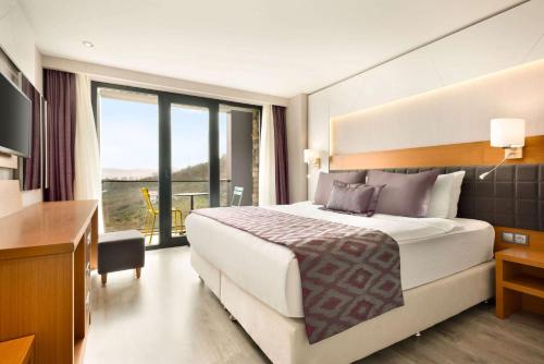 Habitación de hotel con cama grande y balcón. en Ramada By Wyndham Giresun Piraziz, en Piraziz