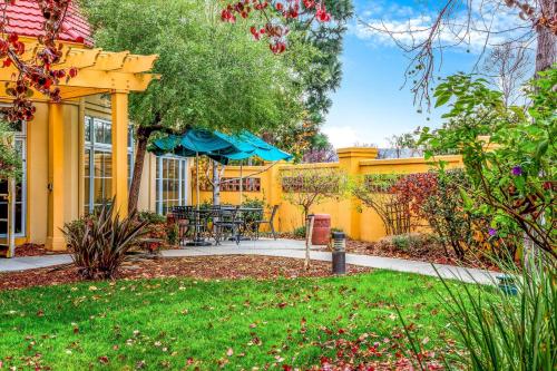a yellow house with a patio with chairs and an umbrella at La Quinta by Wyndham Fremont / Silicon Valley in Fremont
