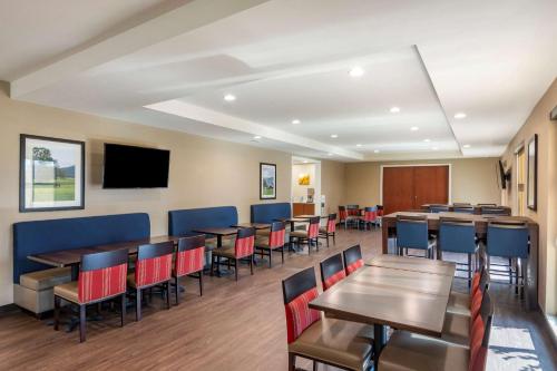 a dining room with tables and chairs and a flat screen tv at Comfort Inn & Suites Charlottesville Hollymead Town Center in Charlottesville