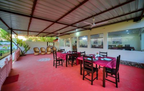 a dining room with red tables and chairs and a ceiling at Ranthambore Nature Camp Resort in Sawāi Mādhopur