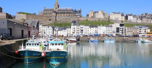 un groupe de bateaux amarrés dans un port avec des bâtiments dans l'établissement Baie du mont saint michel - 6 personnes - Spa privatif, à Roz-sur-Couesnon