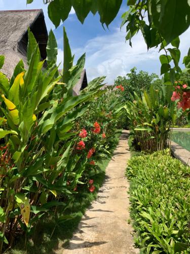 a garden with red flowers and green plants at Three Little Birds Resort in Anda