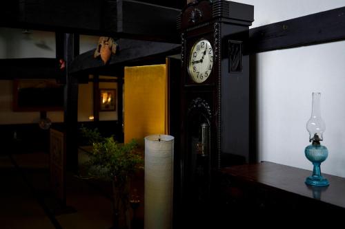 a grandfather clock sitting on a table in a room at Busuitei in Hida