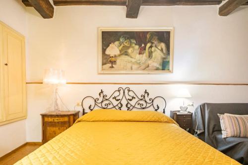 Un dormitorio con una cama amarilla con una pintura en la pared en Vicolo Curtatone 30, en Foiano della Chiana