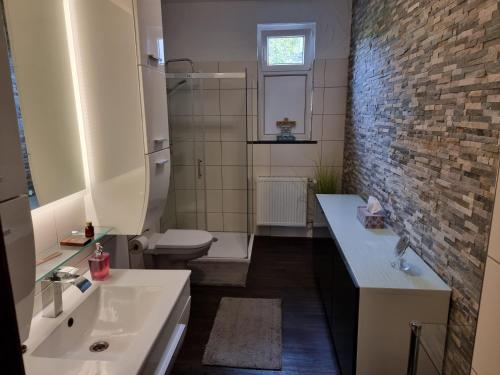 a bathroom with a white sink and a brick wall at Ferienwohnung Stadtvilla in Magdeburg